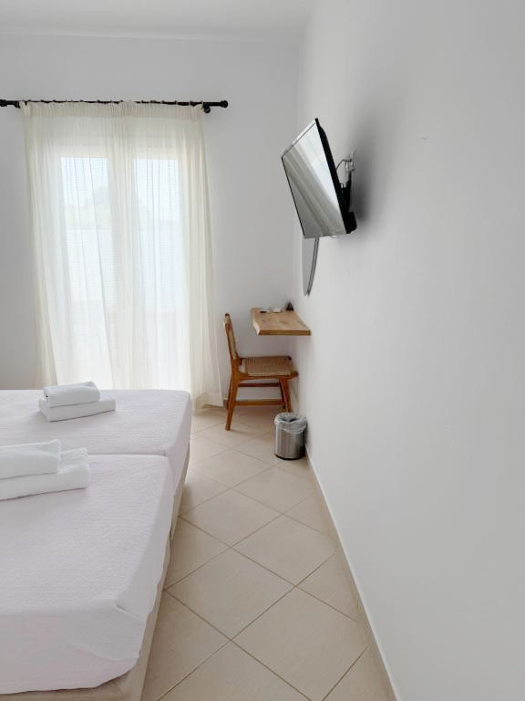 Double or Twin Room with wall-mounted TV, dressing table and balcony access at Argo Rooms Antiparos.
