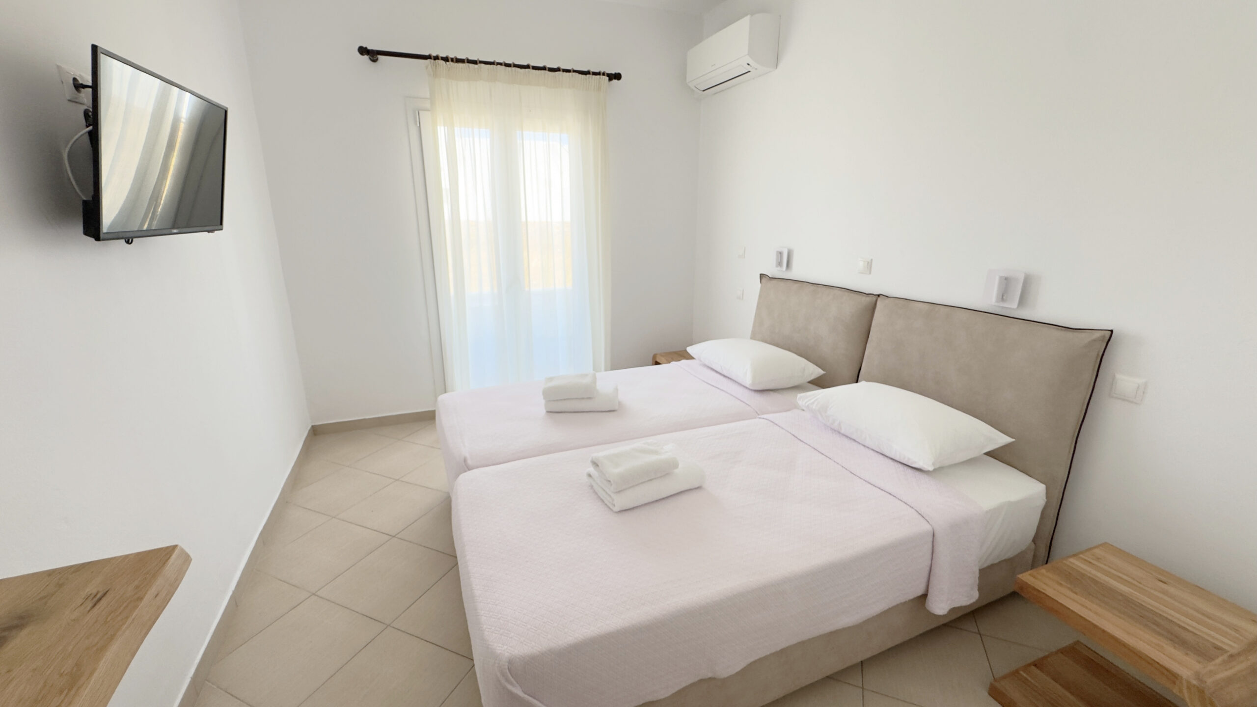Double or Twin Room with two beds, wall-mounted TV and private bathroom area at Argo Rooms Antiparos.