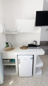 Fully equipped kitchenette with stovetop, sink, fridge, kettle, TV, crockery and cutlery at Argo Rooms Antiparos