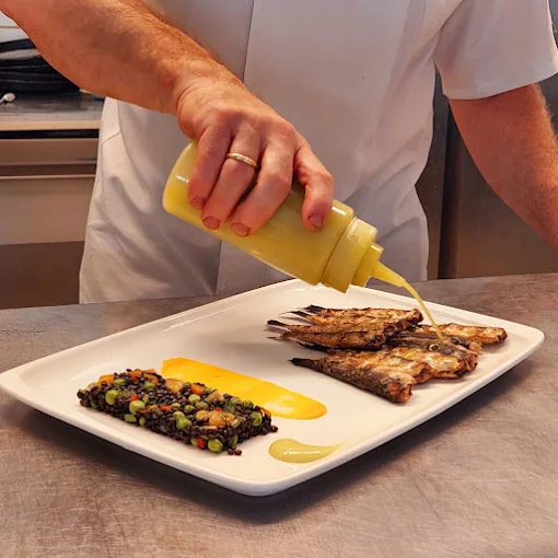 Chef adding sauce to a grilled fish dish at Argo Restaurant Antiparos